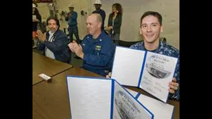 Doug Lounsberry (left) and Cmdr. Joe Tuite (center) applaud as Cmdr. Jon Haydel, commanding officer of San Diego (LPD 22), holds up the ceremonial document acknowledging the ship's custody transfer from Huntington Ingalls Industries to the U.S. Navy. Lounsberry is vice president of the LPD 17 Program at Ingalls. (Photo: HII)