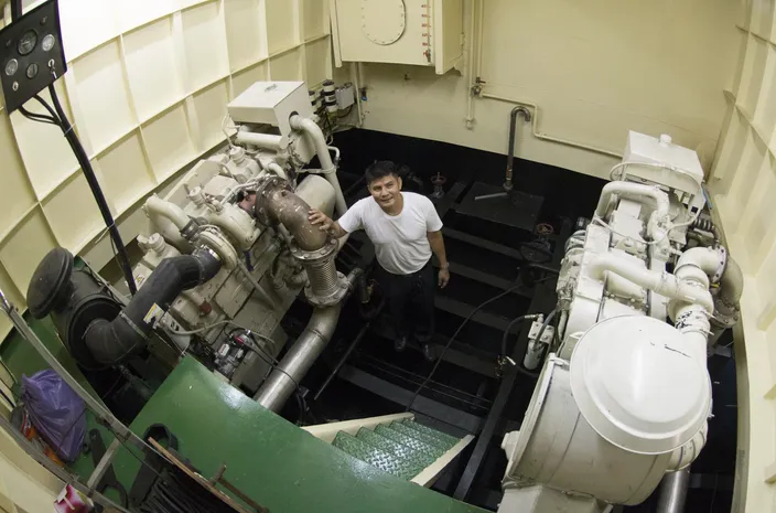 Port Captain Mitr Daiwong standing in the port-site engine room with one of the 600 HP, Cummins KTA19-M main engines. The NT855 150 kW genset is to his left. (Photo credit: Haig-Brown/Cummins Marine)