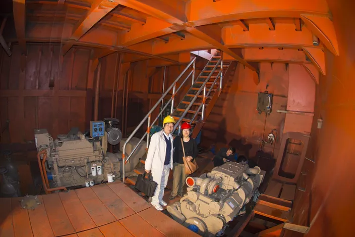Liang Zhong De, deputy general manager, Guang Zhou Shun Fung Engineering Ltd.; stands with Cummins’ southern manager, Linda Zhang, in the starboard side engine room of the crane barge. The KTA19-D genset is to the left, and the KT38-m propulsion engine is to the right (Haig-Brown photo courtesy of Cummins Marine)