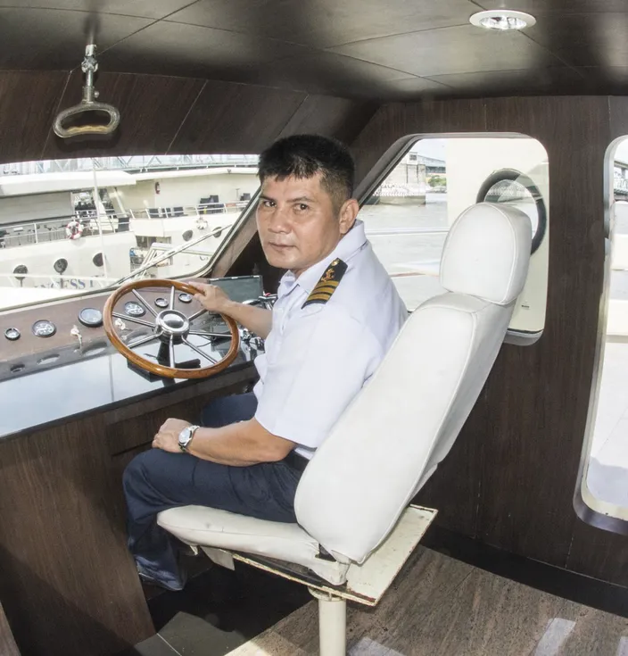 There are eight captains for the seven boats. Port Captain Mitr takes a turn at the helm. (Photo credit: Haig-Brown/Cummins Marine)